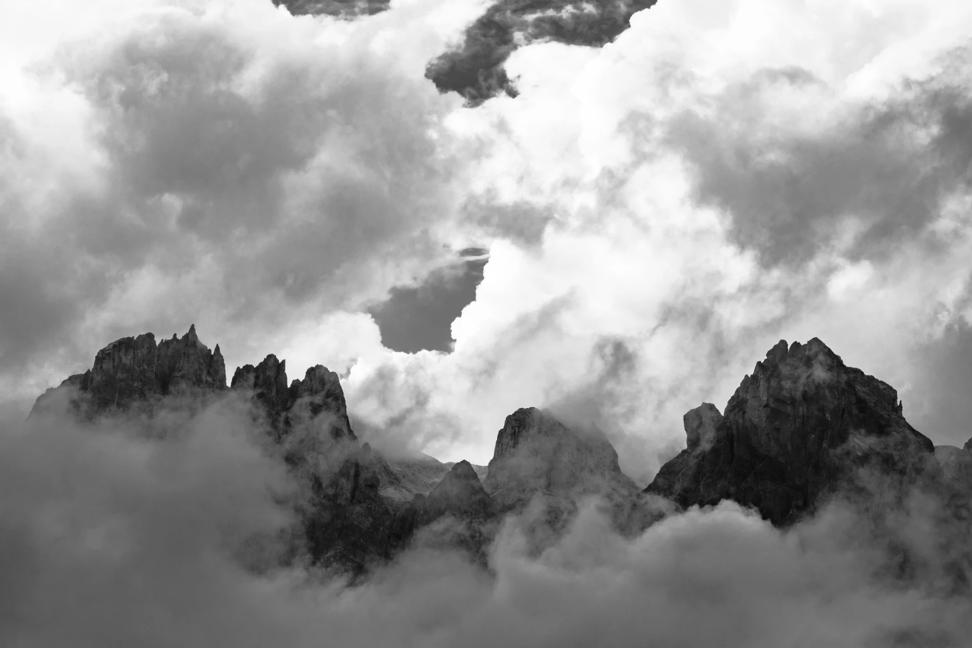 Steile Dolomiten-Gipfel von Nebel umgeben, minimalistisch und monochrom fotografiert, mit ausdrucksstarker, mystischer Atmosphäre.