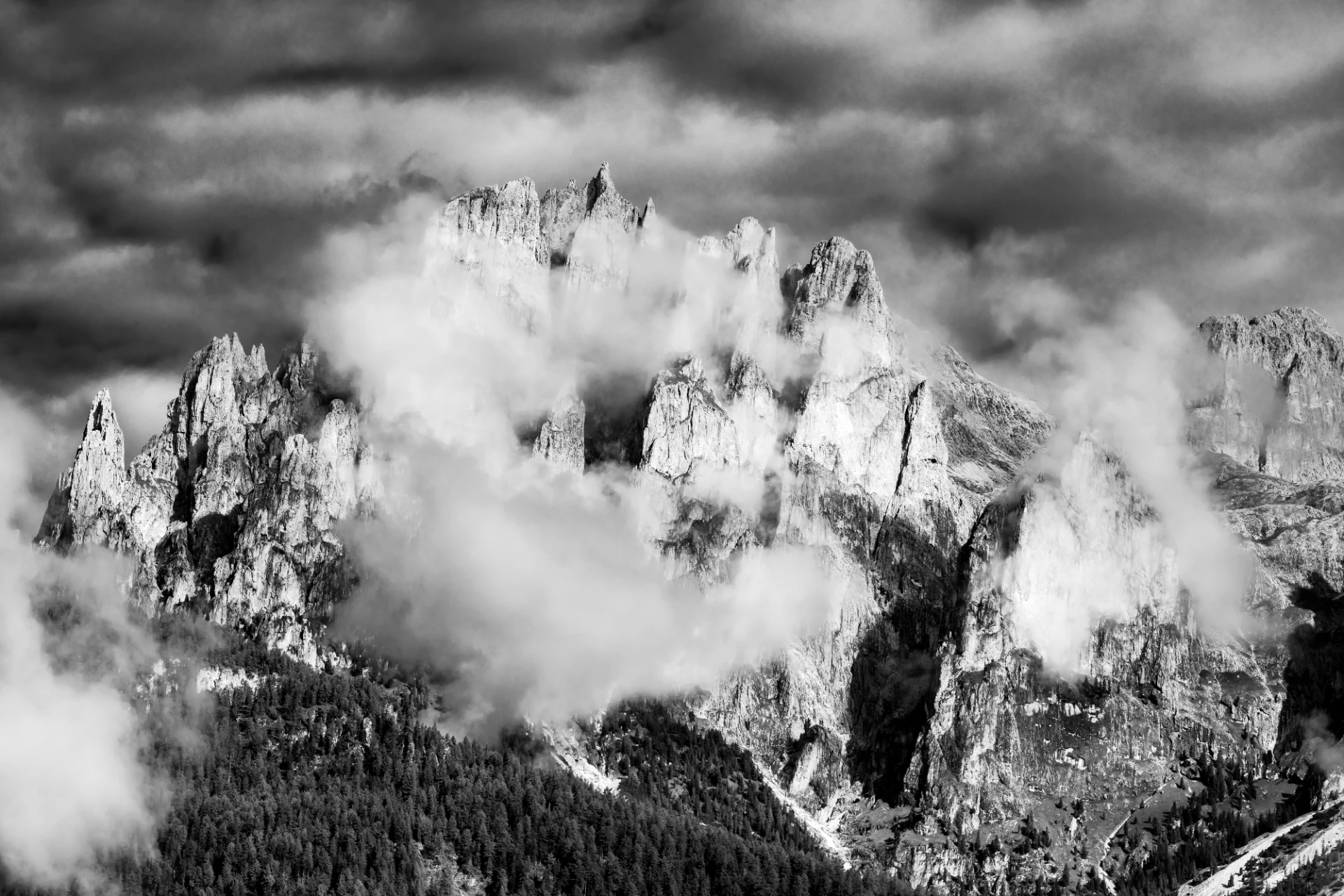 Schwarzweiß-Fotografie der Dolomiten mit schroffen Gipfeln und dramatischem Himmel, klare Linien und majestätische Berglandschaft.