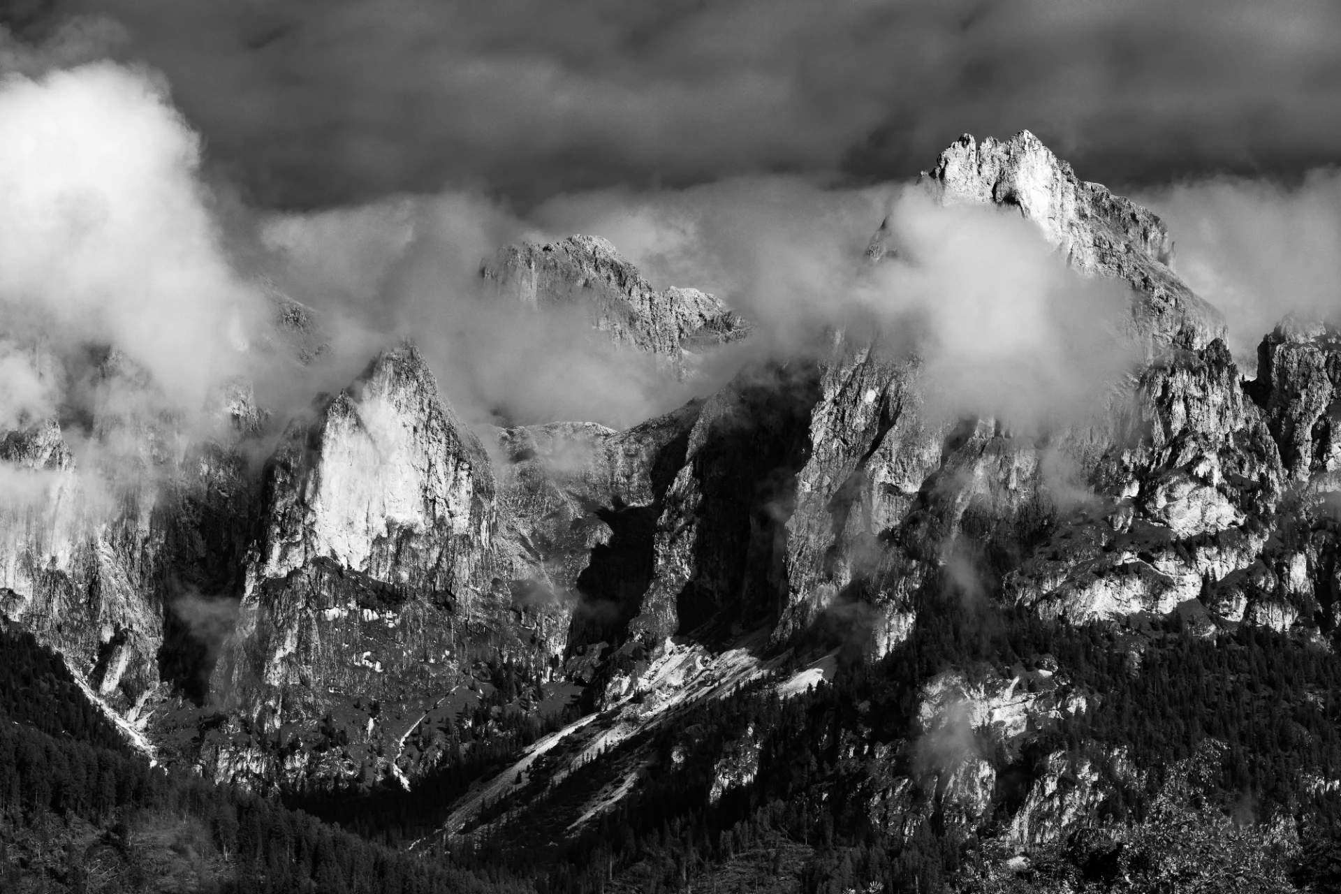 Schwarzweiß-Fotografie eines Dolomiten-Gipfels in Südtirol, umhüllt von sanften Nebelschleiern und schroffen Felsen, dramatisch und mystisch.