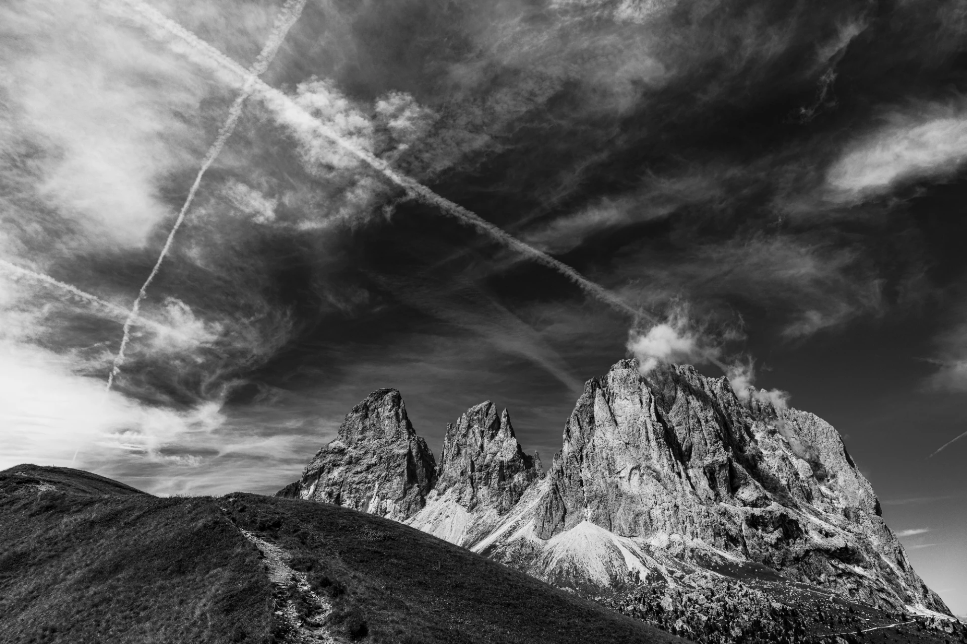 Imposante Langkofelgruppe als kontrastreiche Felsformation vor dramatischem Himmel, in Schwarzweiß fotografiert.
