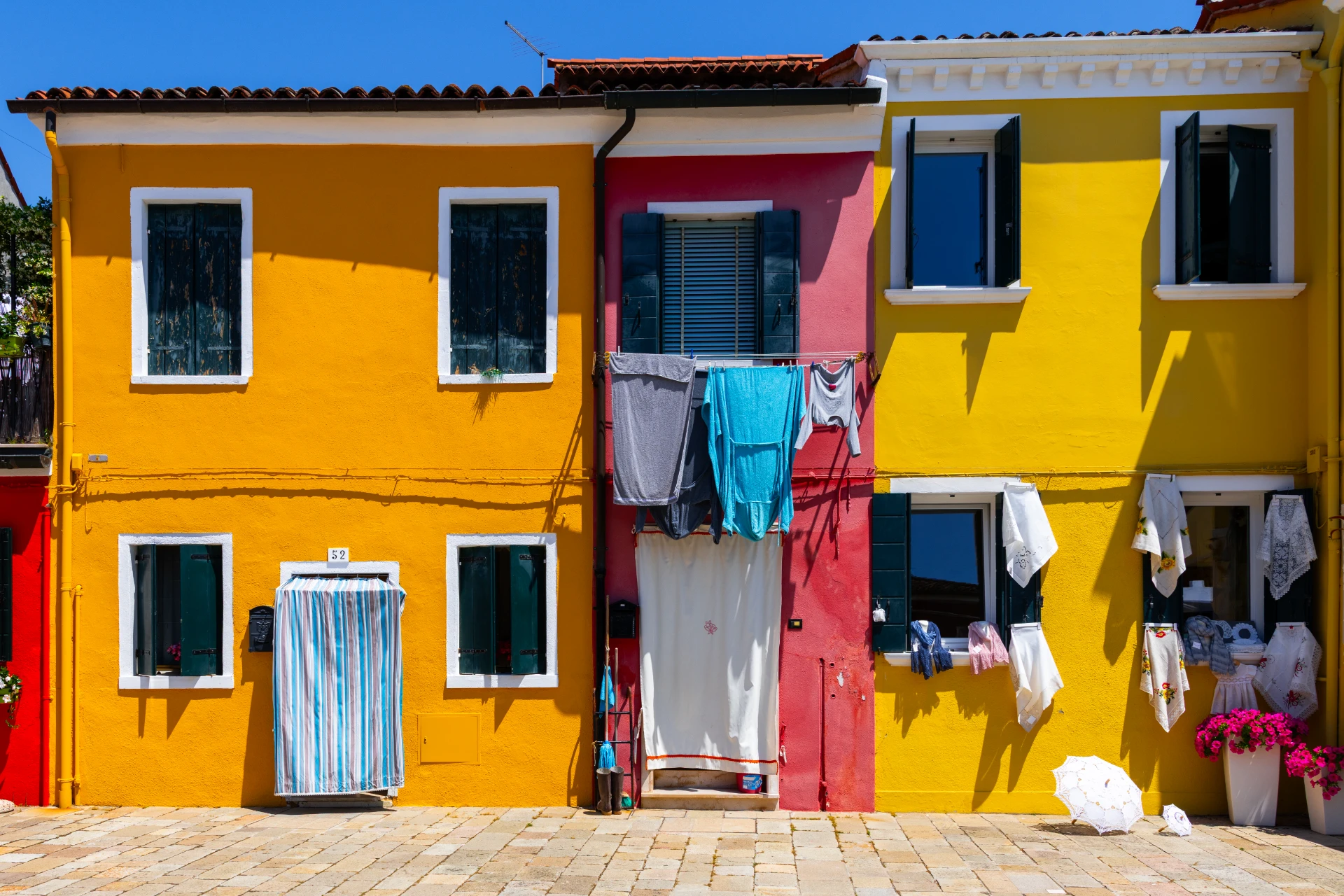 Reihe bunter Häuserfassaden auf Burano, Italien, sonnig und lebendig, urbanes Fotokunst-Wandbild mit vielfältigen Farben