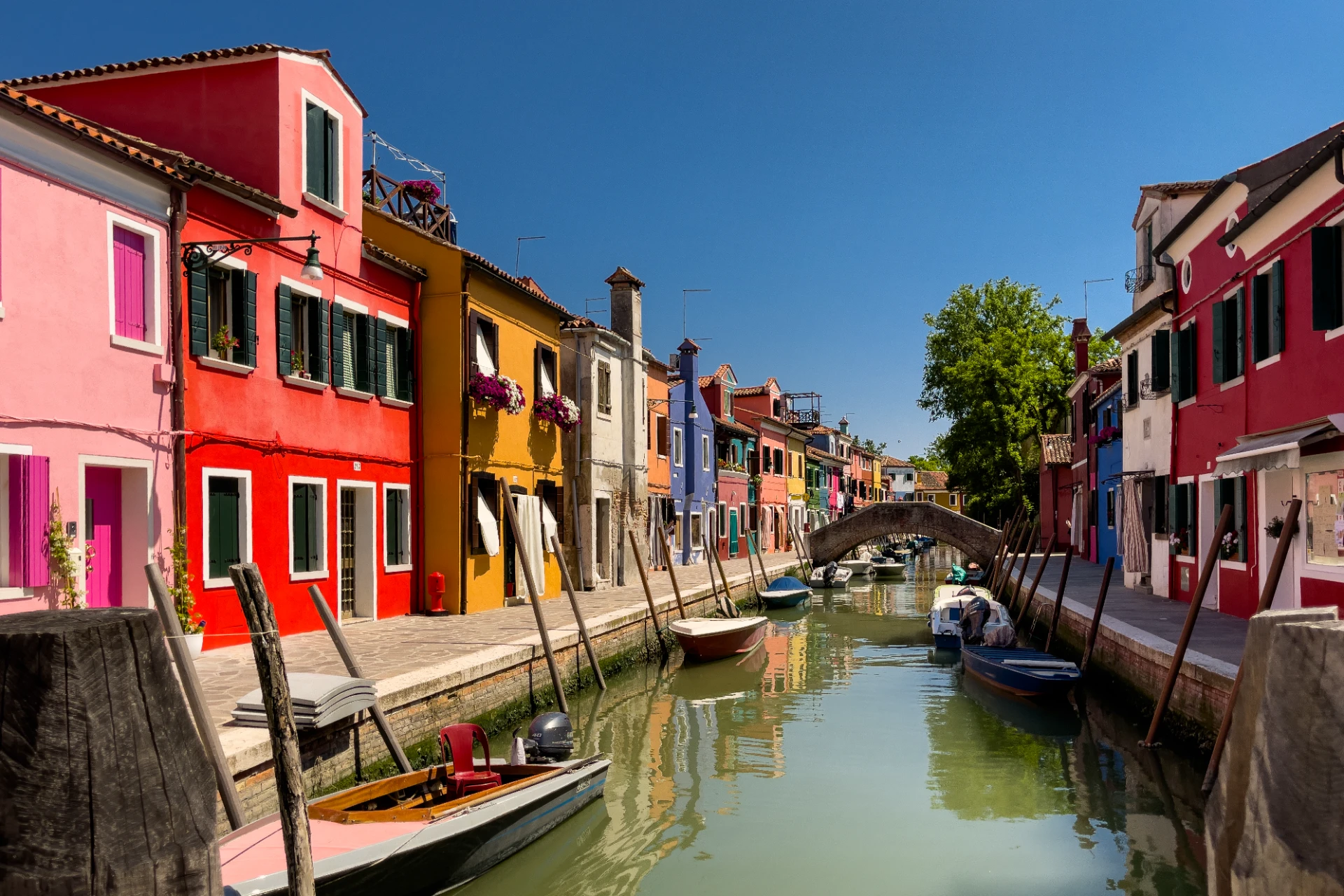 Bunte Häuserfassaden und Kanäle von Burano, Italien, mit farbenfrohen Spiegelungen im Wasser, urban und lebendig inszeniert