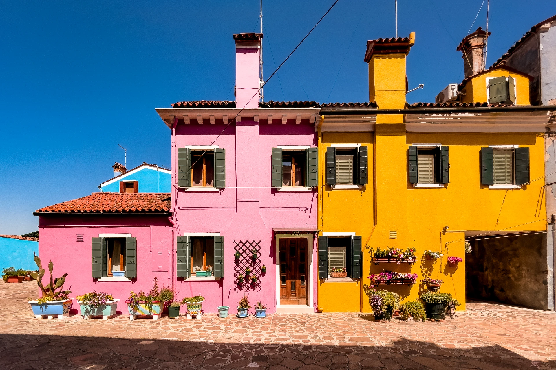 Reihe bunter Hausfassaden auf Burano, Italien, leuchtend und farbenfroh im Tageslicht, urbanes Motiv für große Wandbilder
