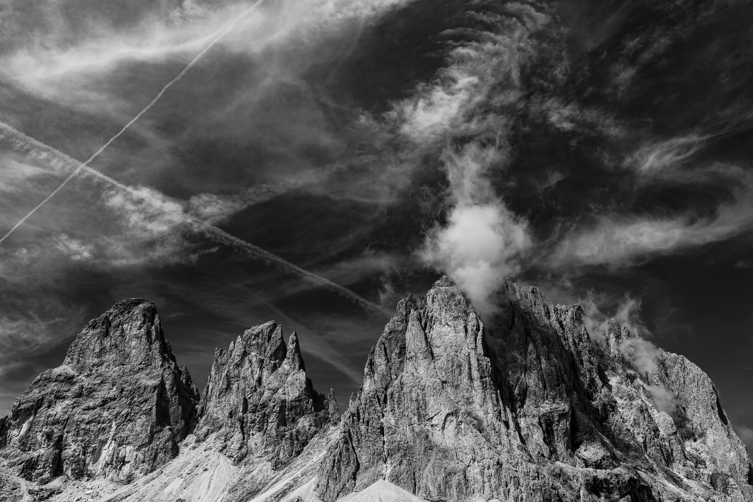 Schroffe Felsen der Langkofelgruppe in Trentino-Südtirol, dramatisch in Schwarzweiß fotografiert unter markantem Himmel, imposantes Naturmotiv.