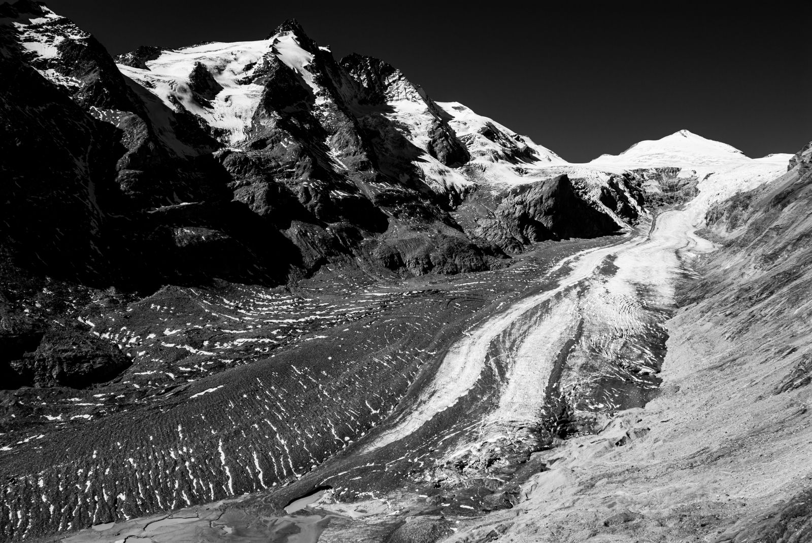 Schwarzweiß-Fotografie der Gletscherlandschaft am Großglockner mit Blick auf die Pasterze, majestätische Berge und weite Natur.