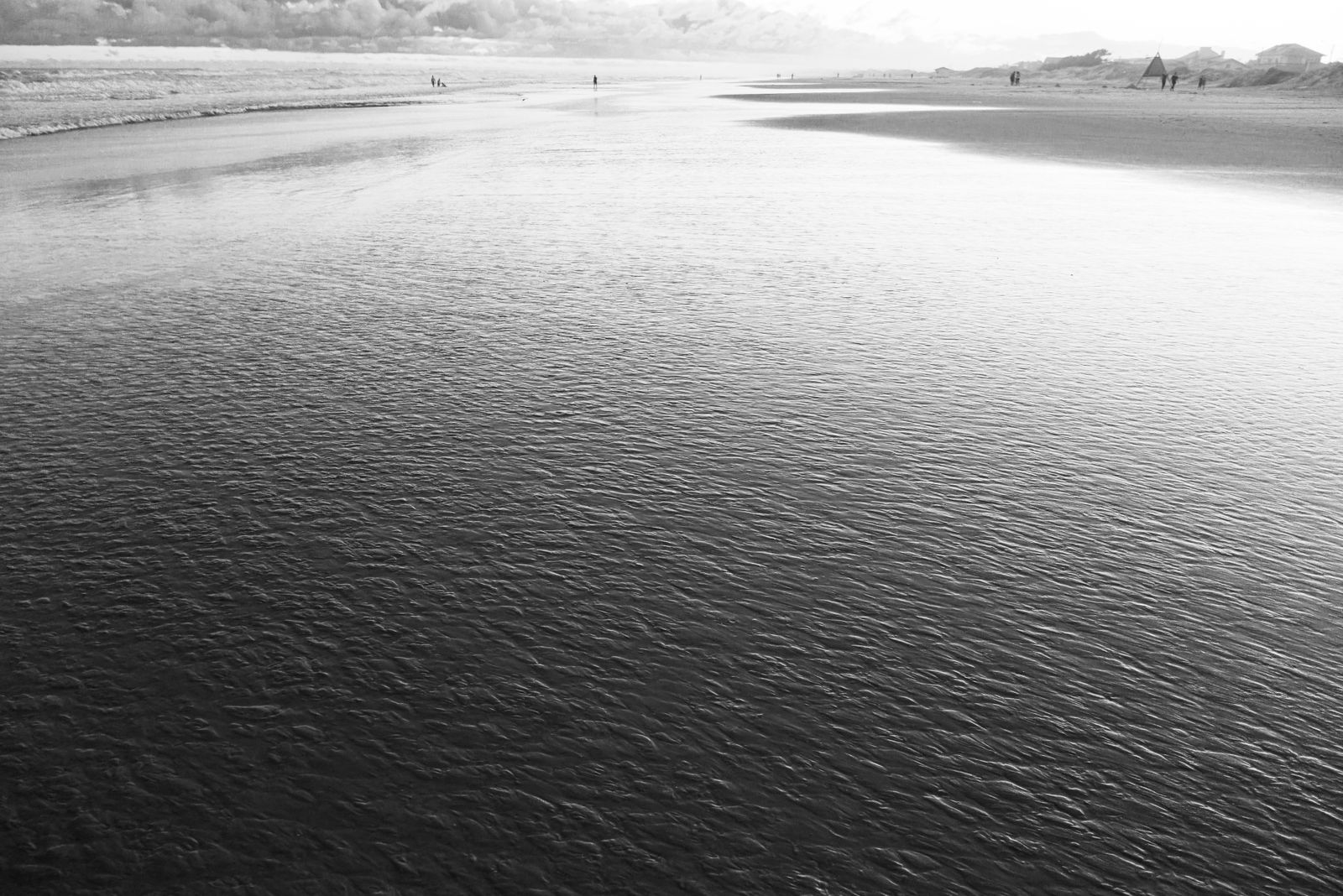 Sanfte Wellen treffen auf ausgedehnten Sandstrand unter weitem Himmel an der brasilianischen Küste, minimalistisch und ruhig fotografiert.