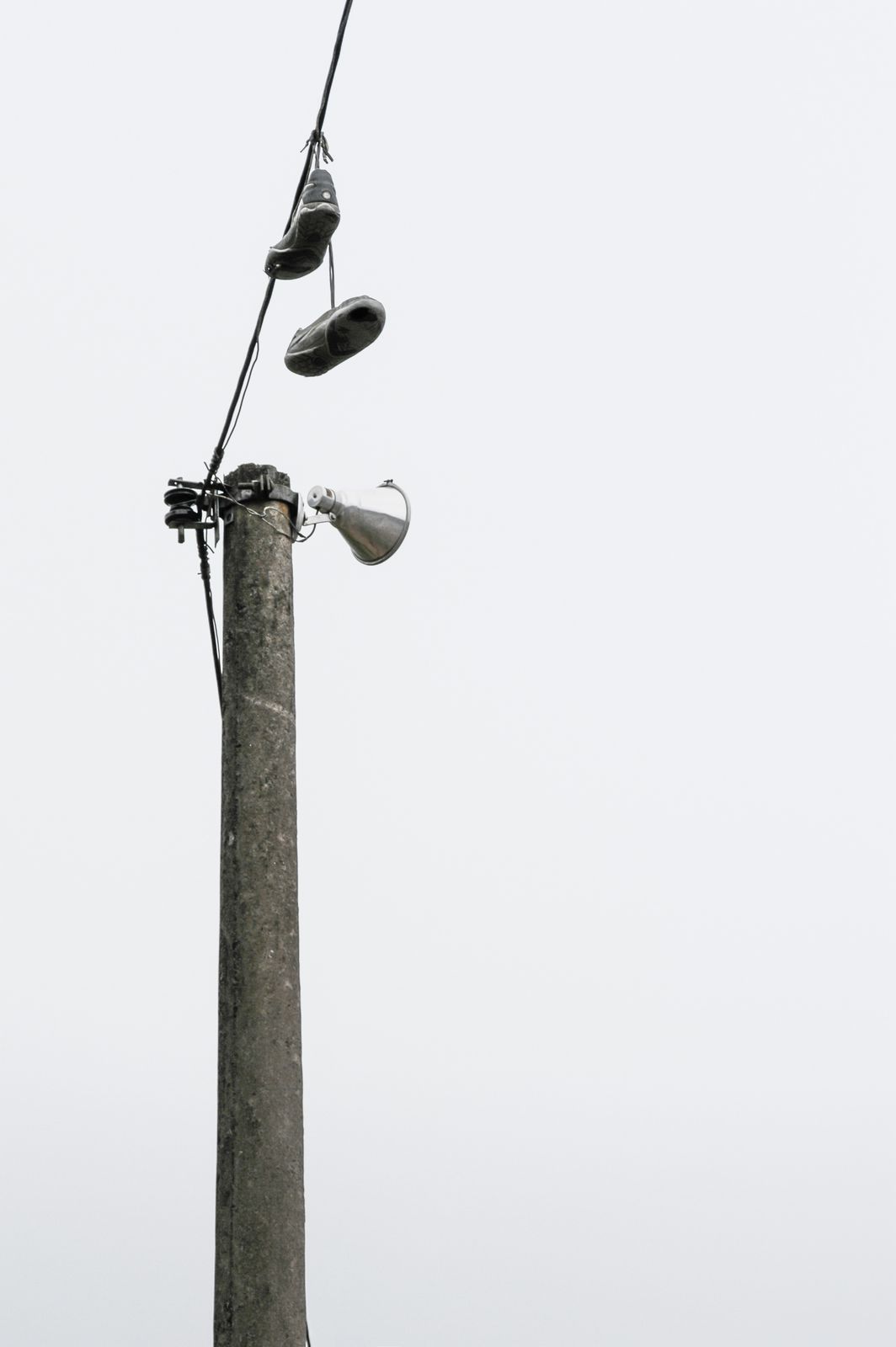 Ein Paar alte Turnschuhe hängt an Stromleitungen vor brasilianischem Himmel, minimalistisch und urban fotografiert.