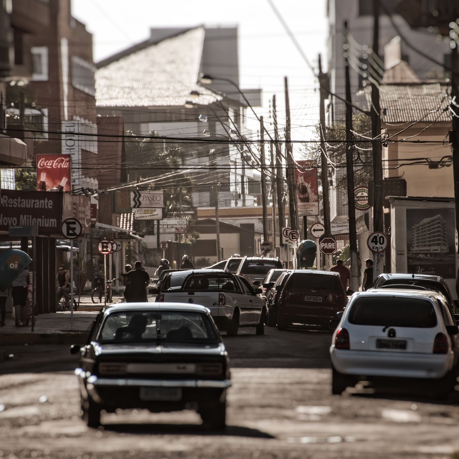 Belebte brasilianische Straßenszene mit Passanten, bunten Häusern und urbanem Flair in dokumentarischem Fotokunst-Stil.