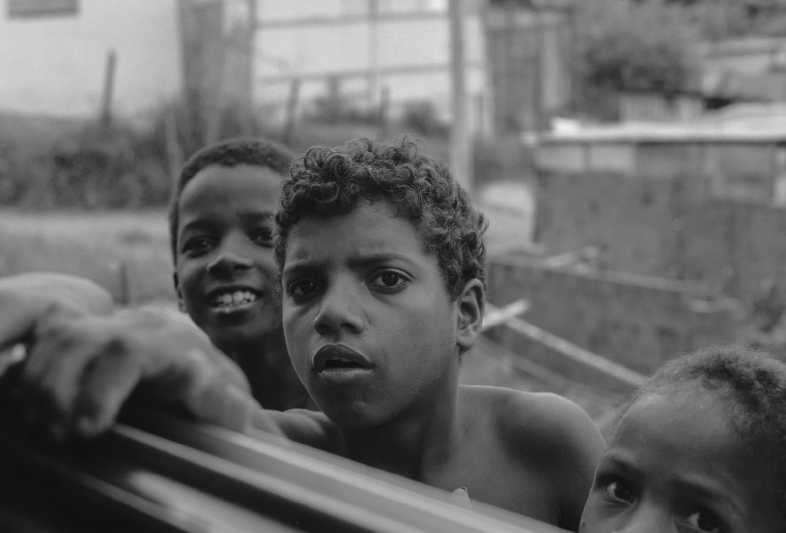 Zwei brasilianische Kinder mit großen, neugierigen Augen und sanftem Lächeln stehen nebeneinander und blicken direkt in die Kamera.