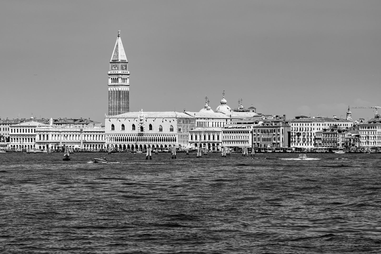 Schwarz-weißes Fotokunstwerk mit der Skyline von Venedig, ruhiges Wasser im Vordergrund, urbane Silhouette im sanften Licht.
