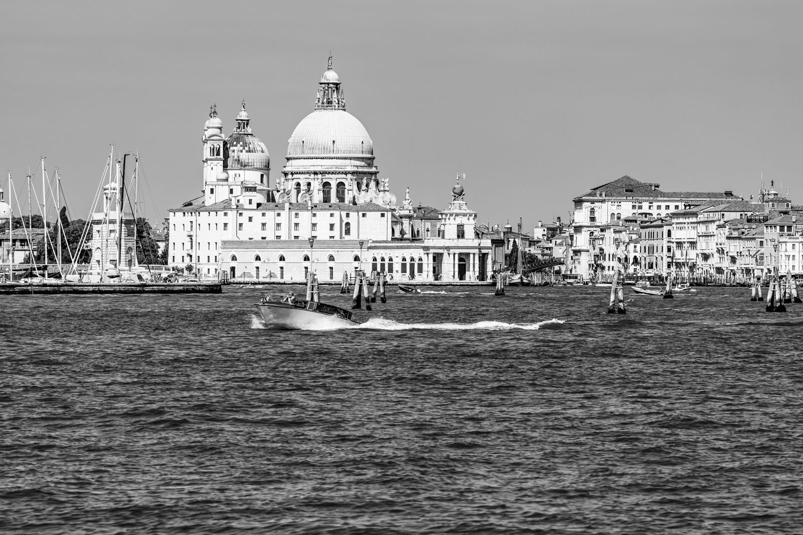 Die Kuppel der Santa Maria della Salute in Venedig spiegelt sich im Wasser, umgeben von sanftem Licht und urbaner Kulisse.
