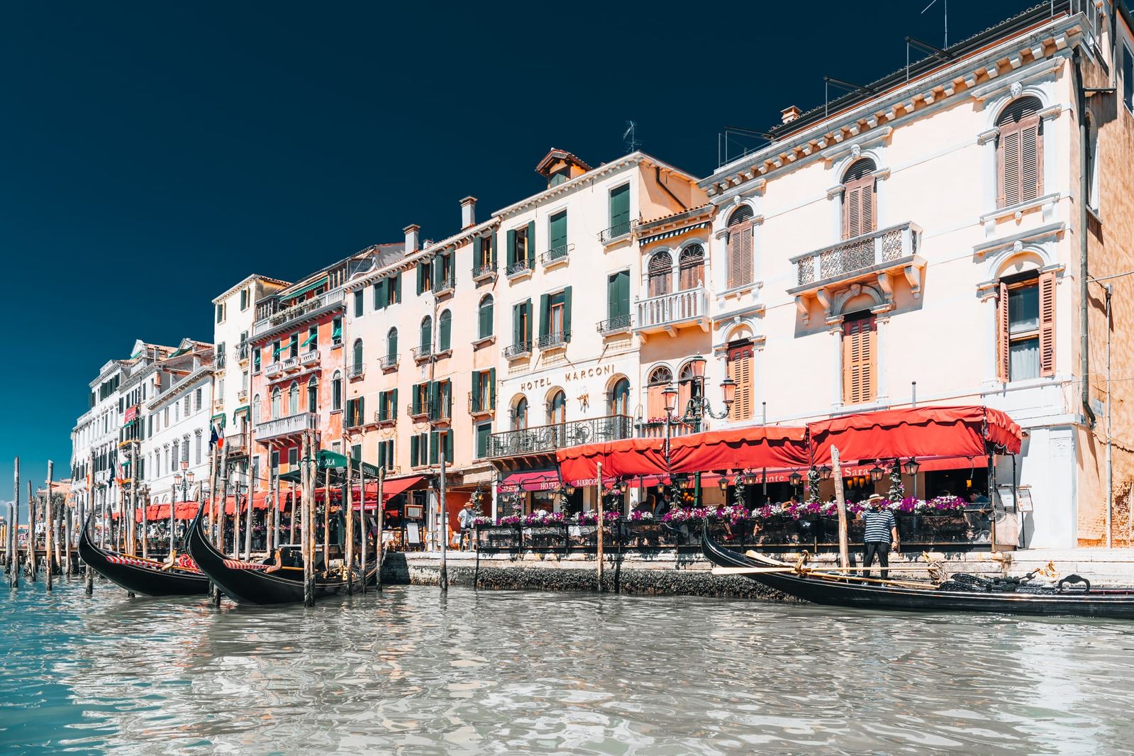 Mehrere Gondeln treiben auf dem Canal Grande vor der Kulisse von San Marco in Venedig, das Bild zeigt sonnige, urbane Atmosphäre.
