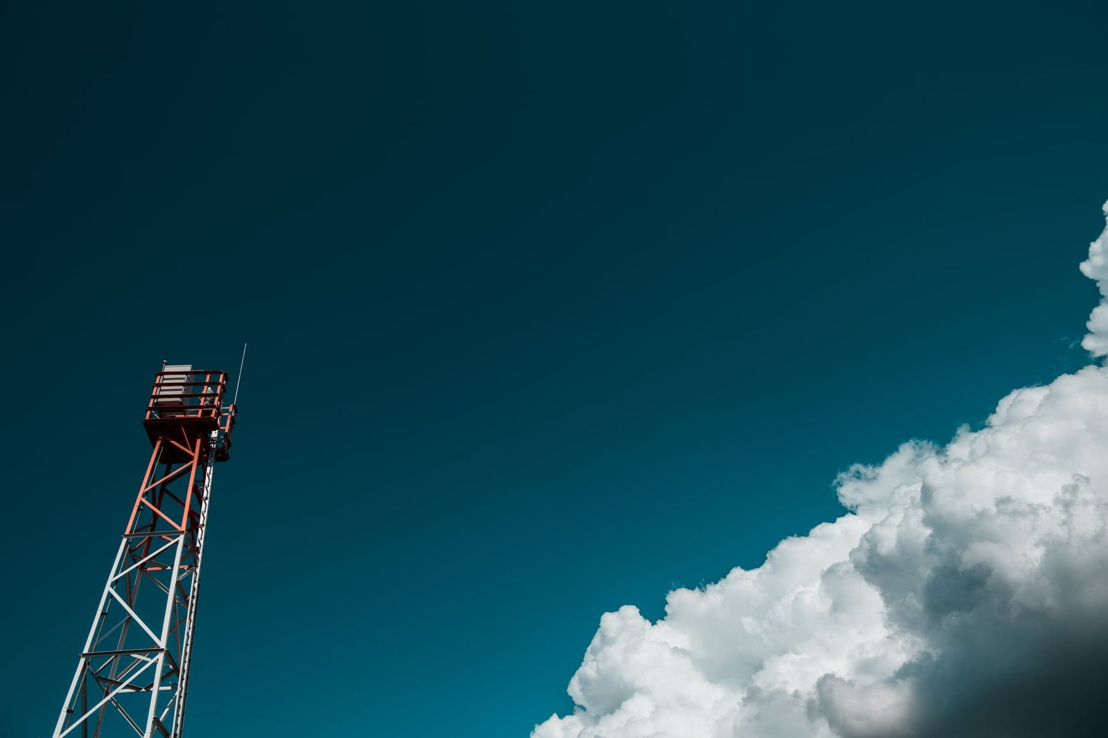 Ein einzelner Beobachtungsturm steht in offener Landschaft unter einem klaren Himmel mit sanften Wolken an der Ostsee.