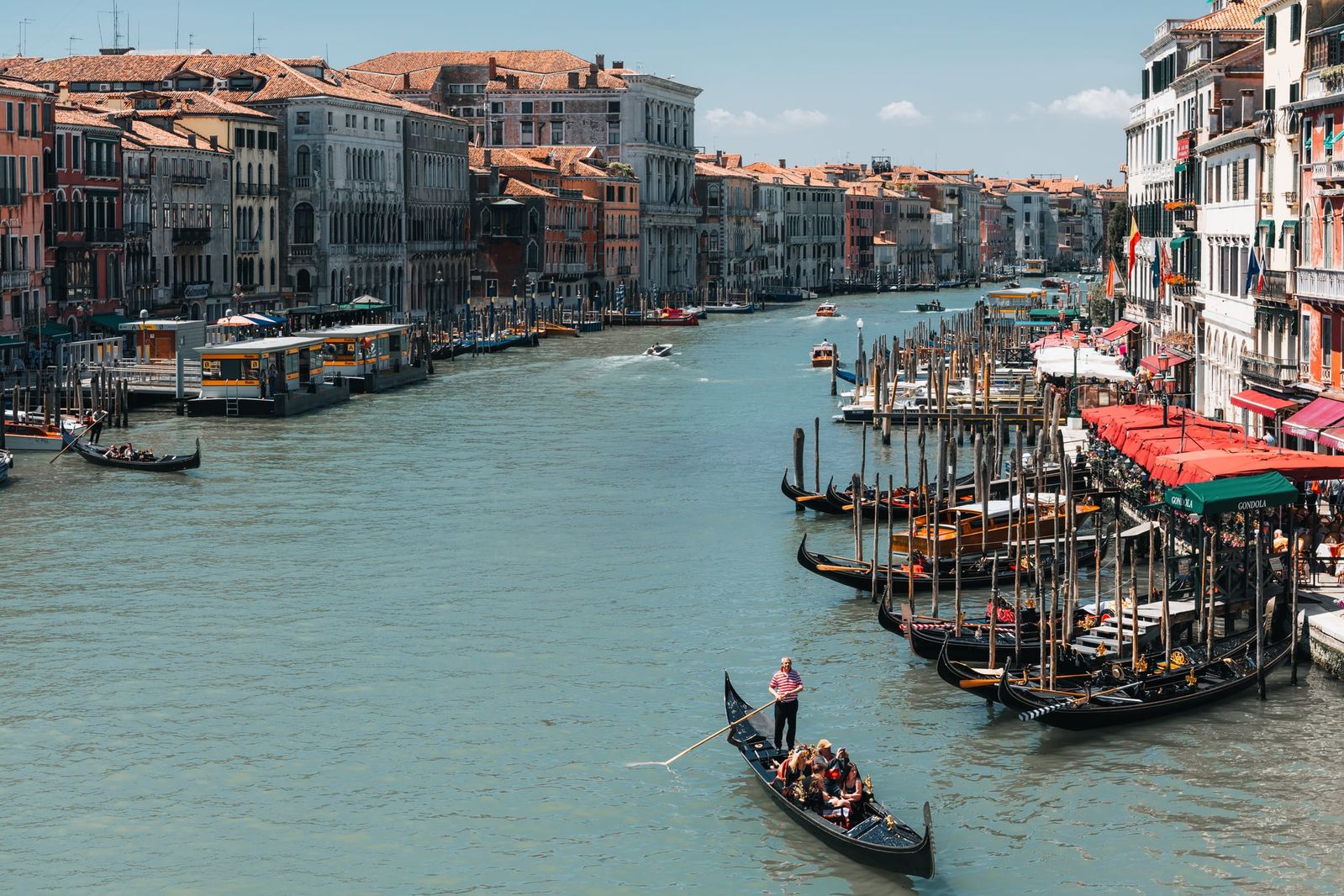 Mehrere Gondeln gleiten sanft über den Canal Grande in Venedig, das Wasser spiegelt das goldene Licht der untergehenden Sonne, im Hintergrund historische Gebäude.