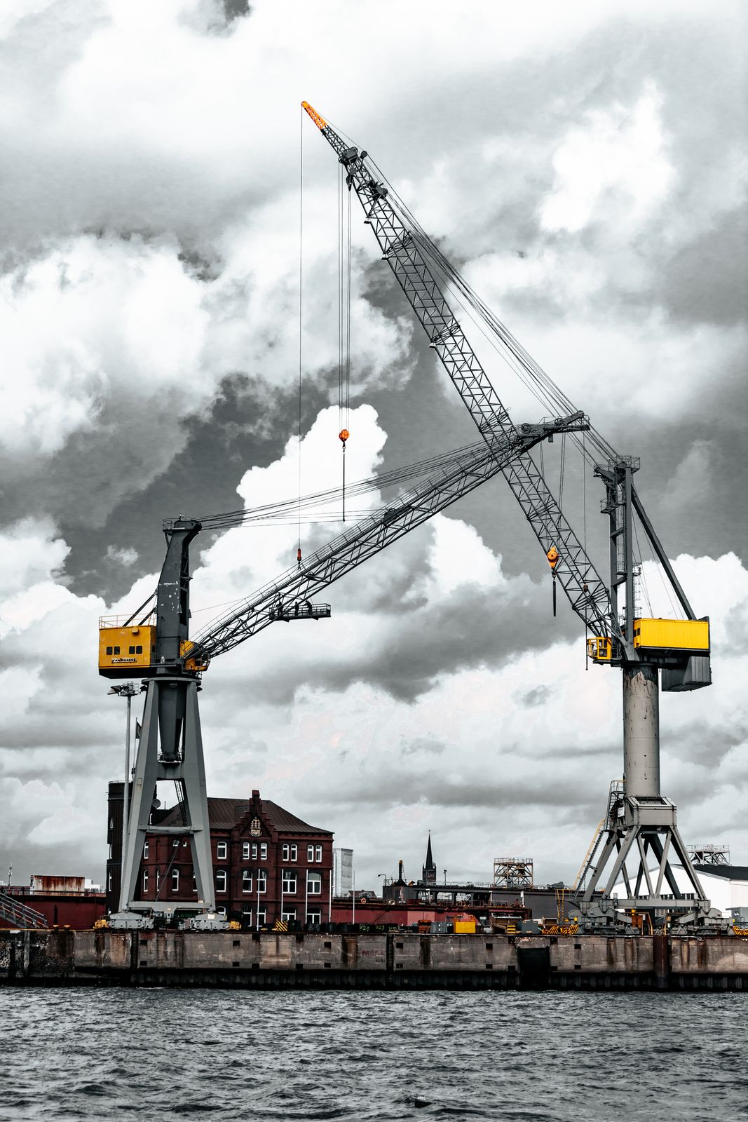 Ein mächtiger Hafenkran steht am Kai vor ruhigem Wasser, umgeben von Stahlstreben und maritimer Atmosphäre in urbaner Umgebung.
