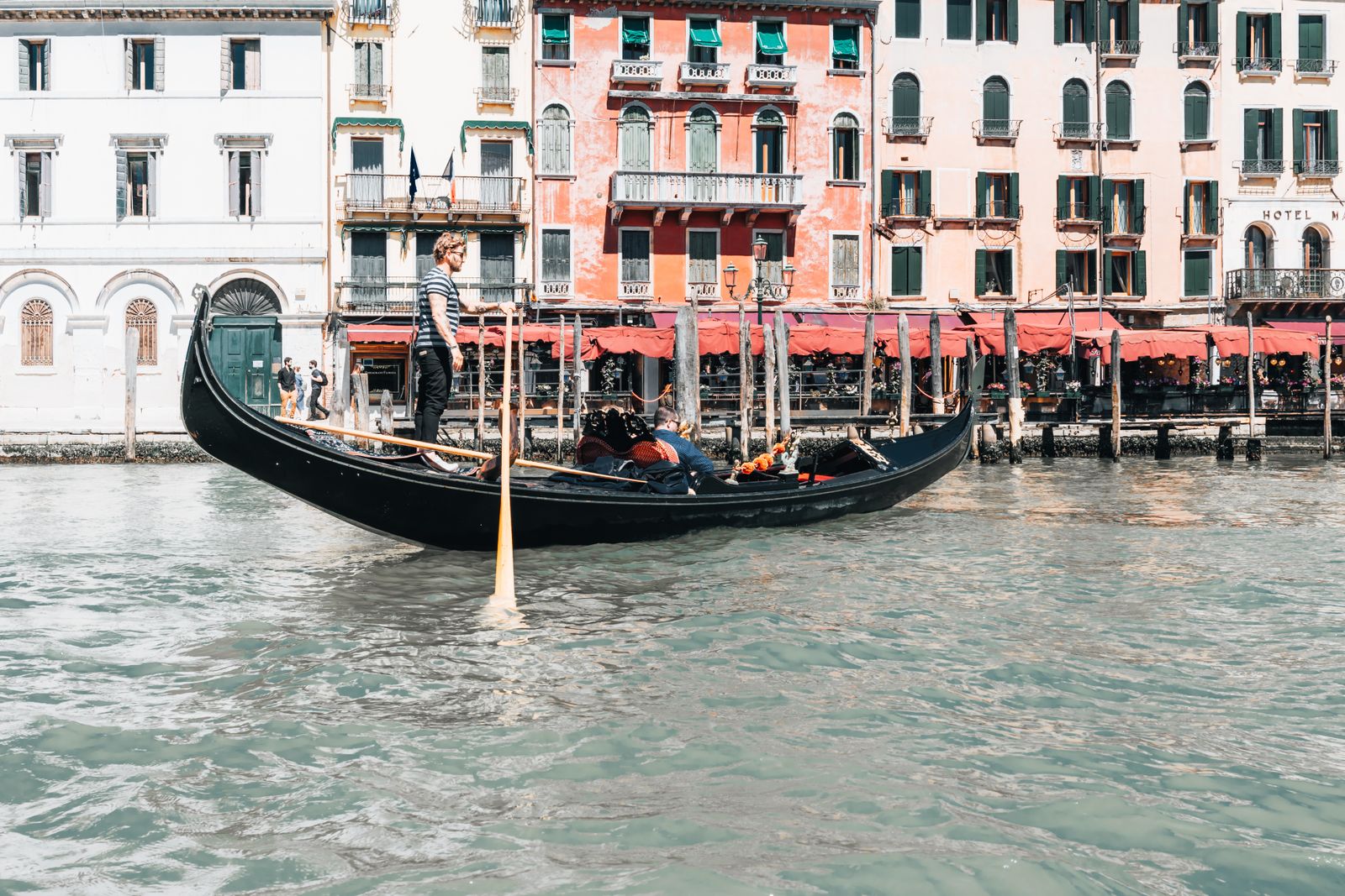 Eine venezianische Gondel gleitet auf ruhigem Wasser, im Hintergrund die beleuchteten Silhouetten von San Marco unter sanftem Licht.