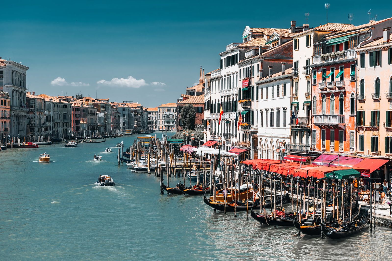 Der Canal Grande in Venedig im sanften Sonnenlicht, kunstvolle Fassaden spiegeln sich im Wasser, urbanes, lebendiges Stadtbild.
