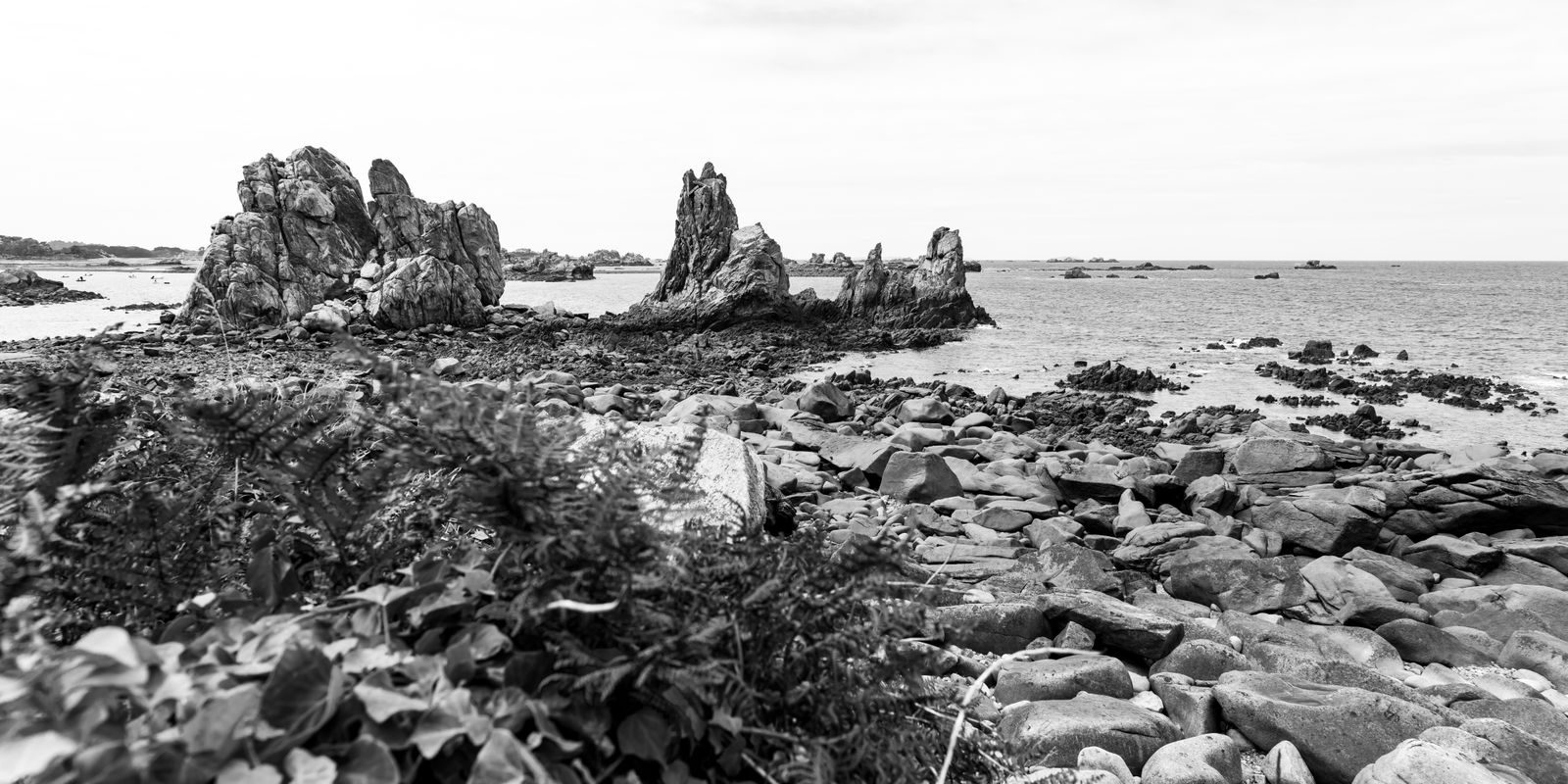 Felsige Küste mit rauem Gestein, Wellen und dramatischem Himmel an der Bretagne, minimalistisch und ruhig fotografiert
