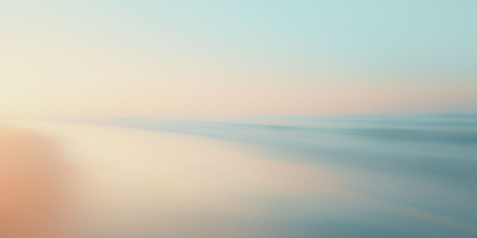 Panoramaaufnahme einer sanften Küstenlinie im Morgenlicht mit ruhigem Ozean, nassem Sand und vielfältigen Farben.