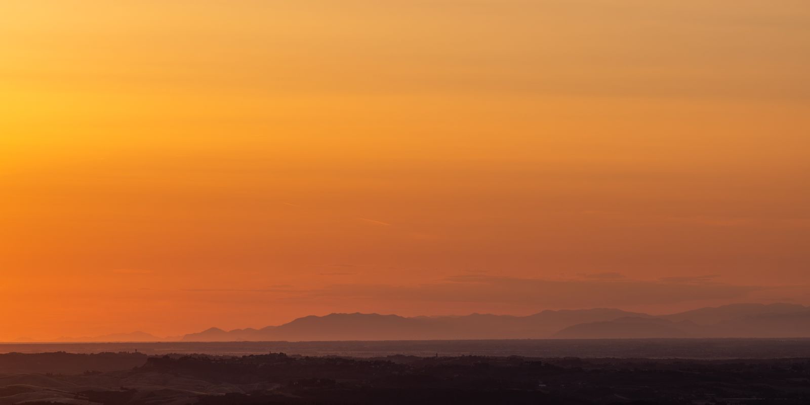 Weite Hügellandschaft in warmes Abendlicht getaucht, sanft geschwungene Hügel mit weichen Schatten und vielfältigen Farben, minimalistisch und ruhig.