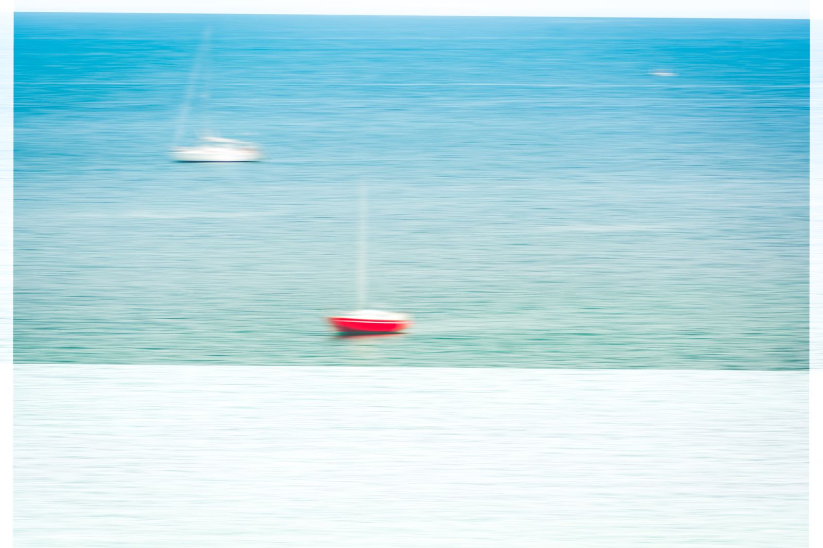 Ein rotes Segelboot gleitet vor der Küste von le-d’Houat über ruhiges, graublaues Meer unter bewölktem Himmel.