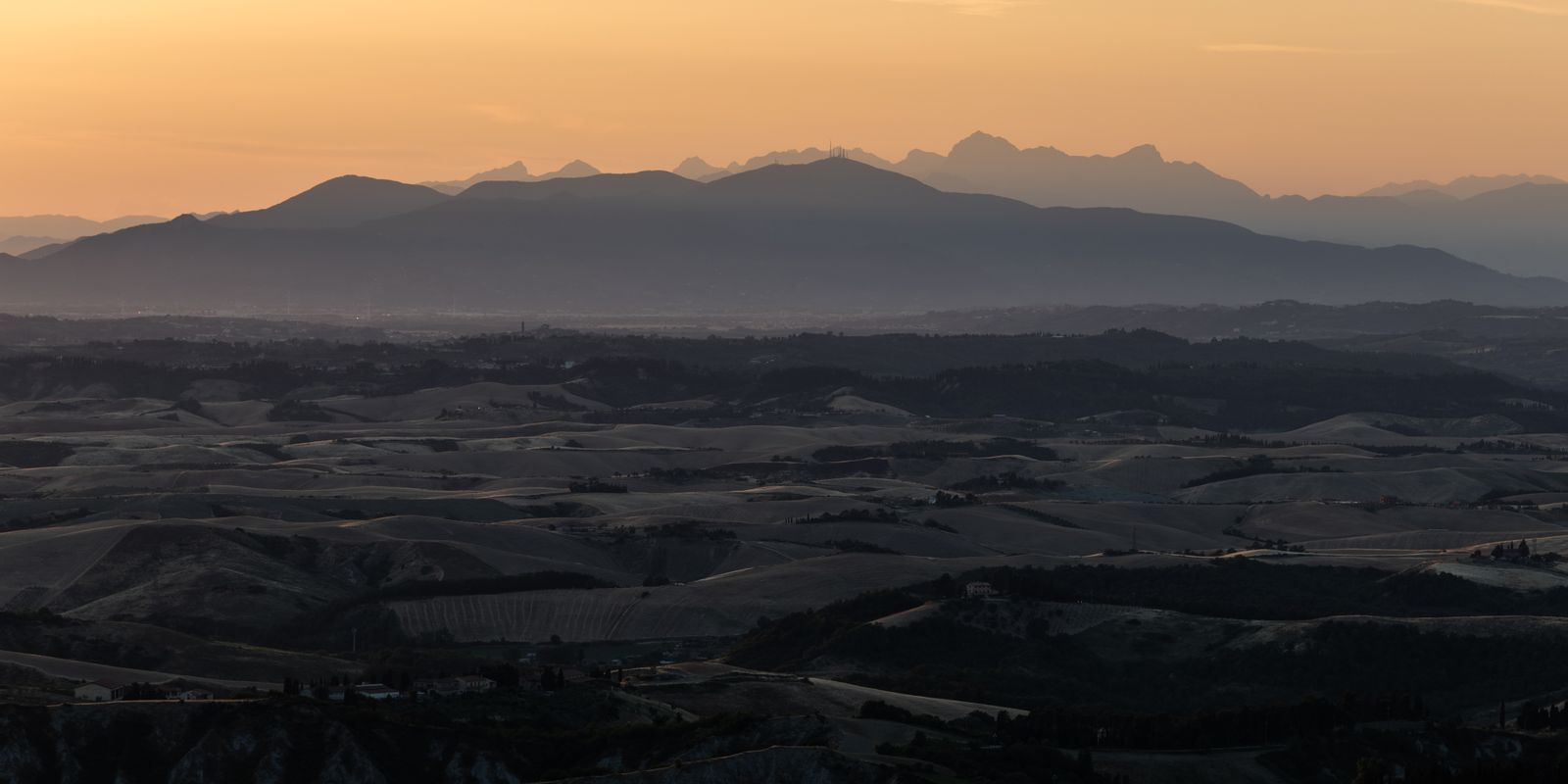 Sanfte grüne Hügel der Toskana im goldenen Abendlicht, minimalistisch fotografiert als Panorama mit weichem Licht und ruhiger Stimmung.