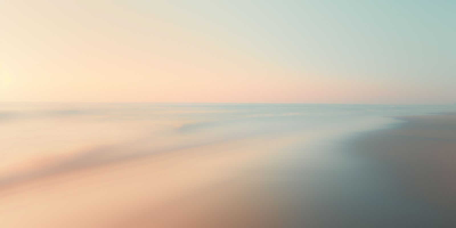 Panoramaaufnahme eines ruhigen Morgens am Meer mit sanftem Licht, zarten Wellen und einem ruhigen Horizont in vielfältigen Farben.