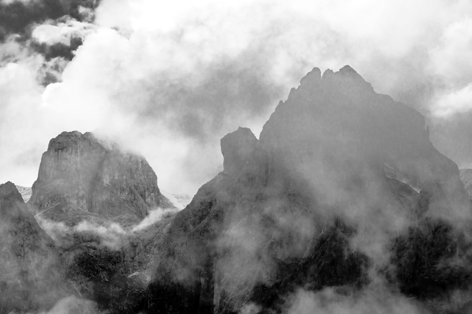 Sanfte Nebelschwaden umhüllen steile Dolomiten-Gipfel in monochromem, minimalistischem Stil. Mystische Berglandschaft mit ruhiger Ausstrahlung.