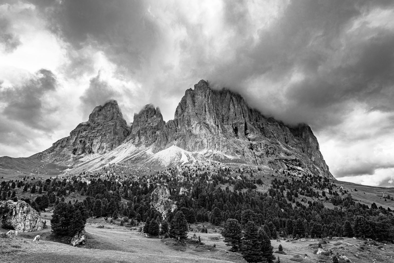 Schwarzweiß-Fotografie einer majestätischen Berglandschaft mit sanften Hügeln und dramatischen Gipfeln bei Wolkenstein in Gröden