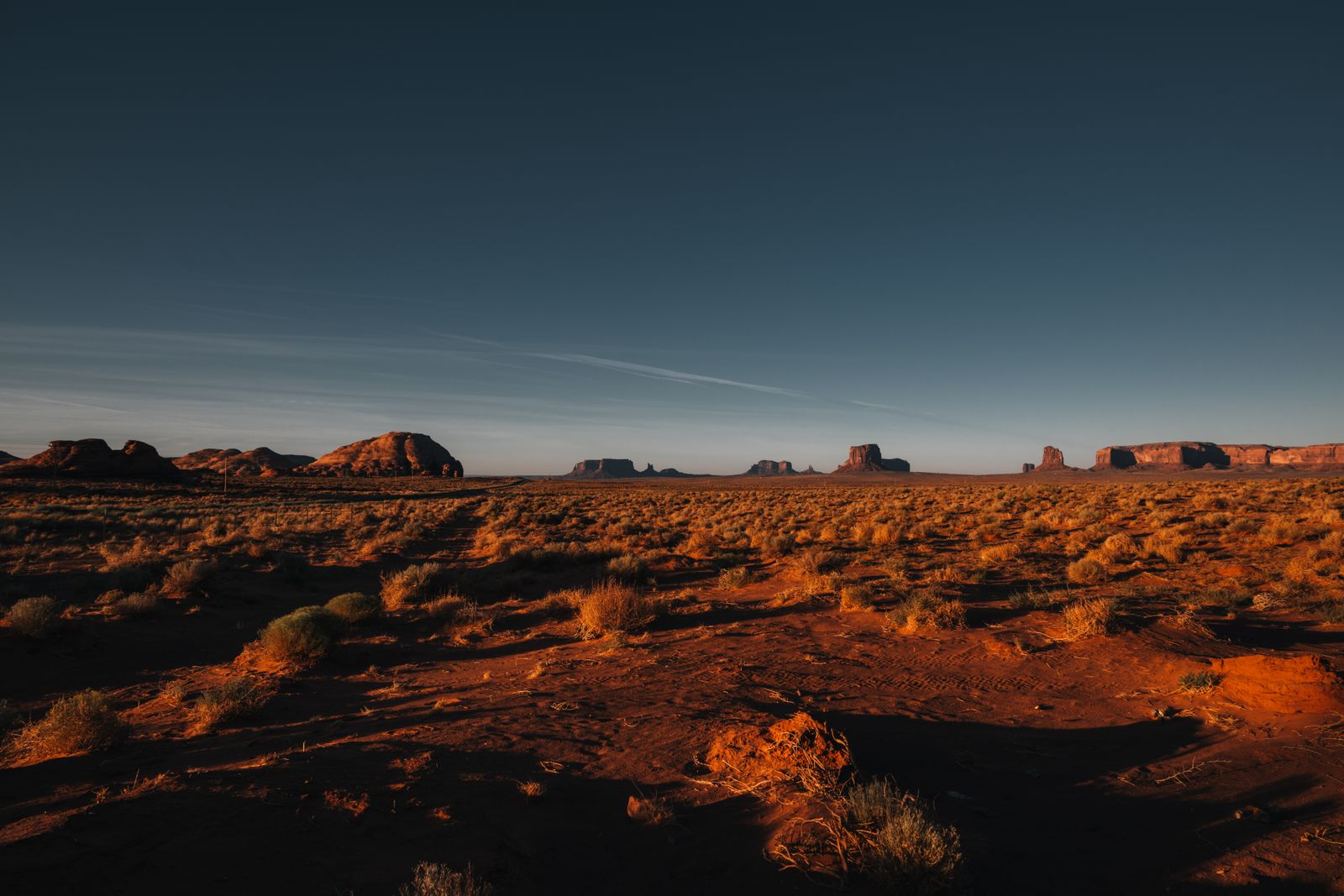Panoramablick auf Monument Valley mit markanten Sandsteinformationen, weiten Ebenen und sanftem Licht in vielfältigen Farben.