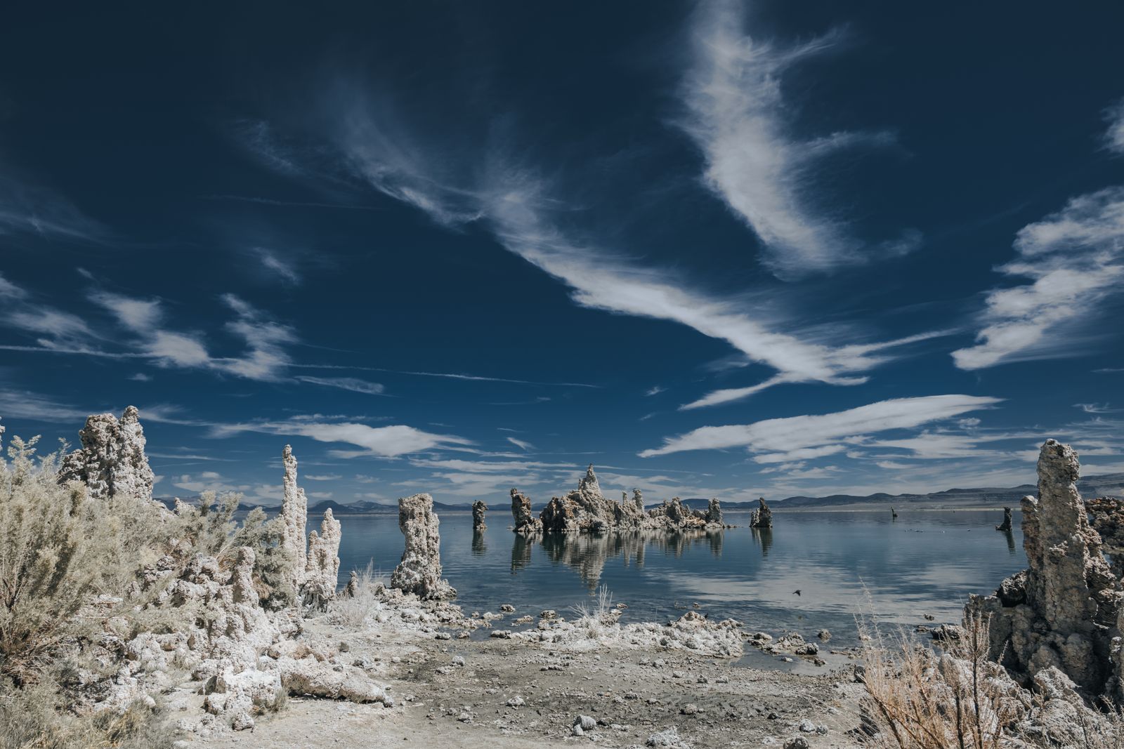 Markante, bizarre Kalktuff-Formationen am Ufer des Mono Lake unter weitem Himmel, ruhige Wasseroberfläche, natürliche Farben, Weite und Stille