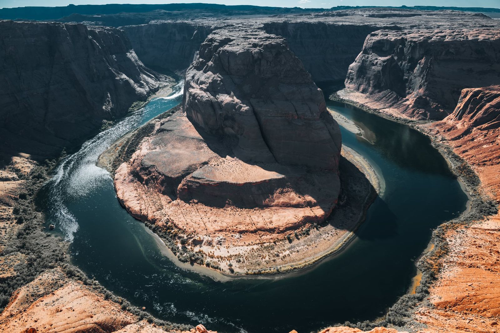 Panoramaaufnahme des Horseshoe Bend in Arizona, USA, mit fließendem Colorado River, umgeben von imposanten Felsen und vielfältigen Farben.