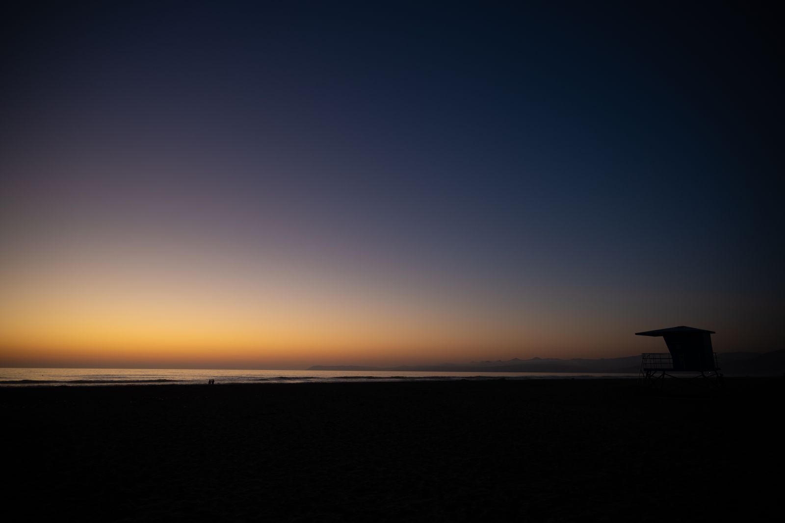 Minimalistisches Wandbild mit amerikanischem Rettungsturm am Strand, sanfter Sonnenuntergang und pastellfarbener Himmel, ruhige Atmosphäre.