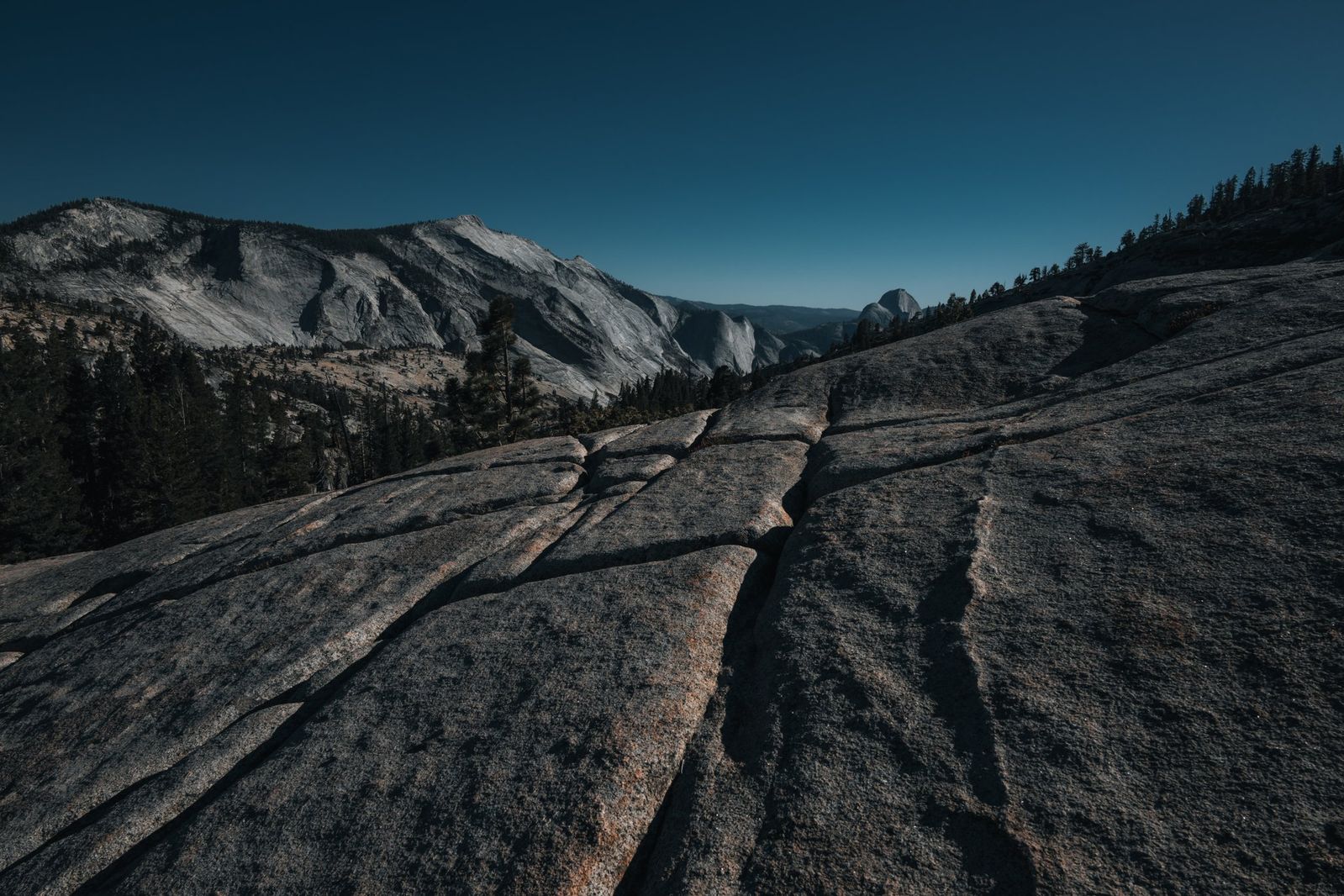 Weitläufige Granitfelsen und majestätische Felsformationen im Yosemite Nationalpark, umgeben von vielfältiger Natur und ruhiger Landschaft.