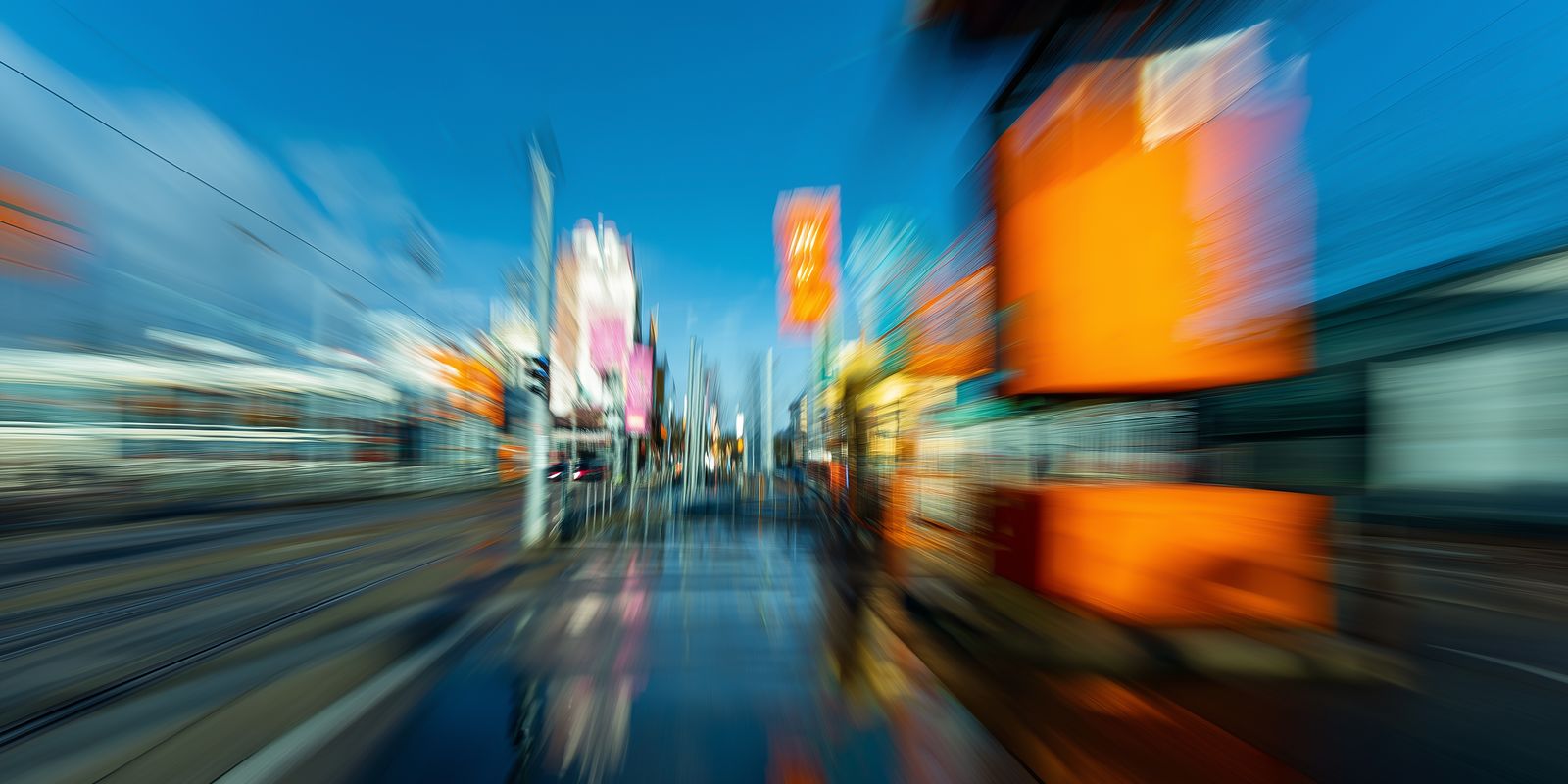 Moderne Fotografie einer urbanen Szene mit Menschen in Bewegung, vielfältigen Farben und abstrakter Bewegungsunschärfe im Panoramaformat.