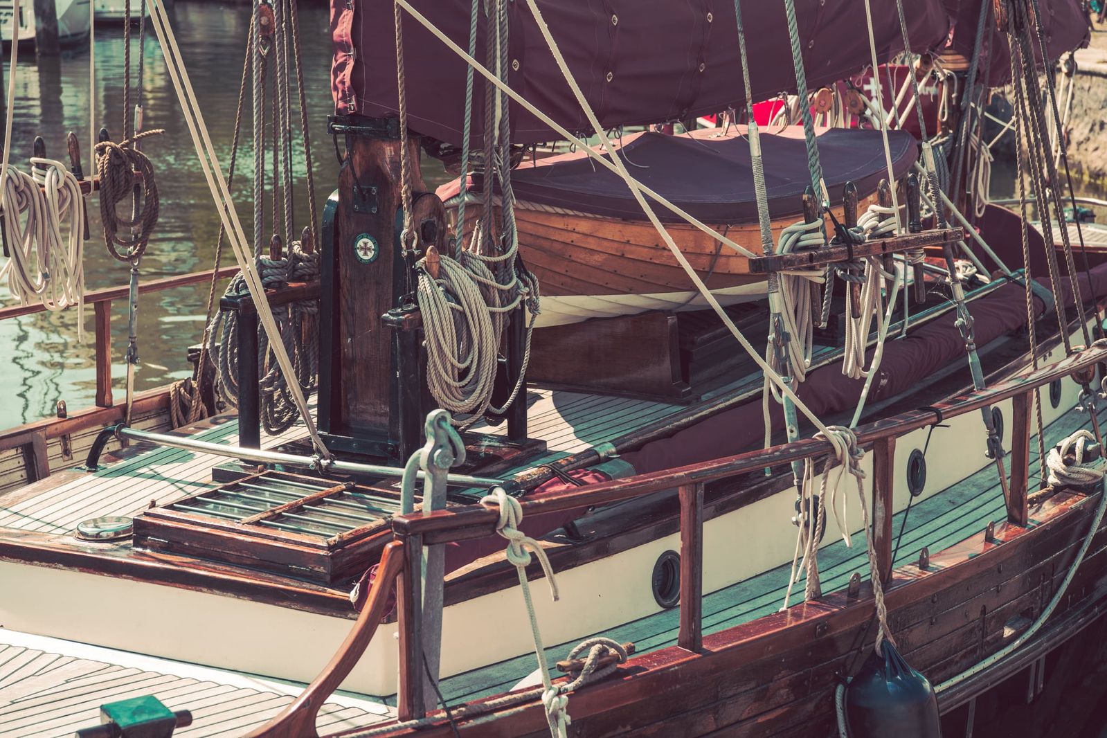 Historisches Segelboot mit weißen Segeln und hohem Mast segelt vor Stralsund auf ruhigem Wasser, dokumentarisch im Vintage-Stil fotografiert.