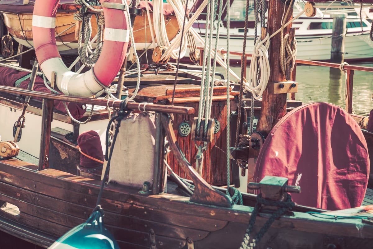 Ein klassisches Holzsegelboot liegt ruhig vertäut an einer Anlegestelle im Hafen von Stralsund, maritimes Vintage-Motiv mit vielfältigen Farben.