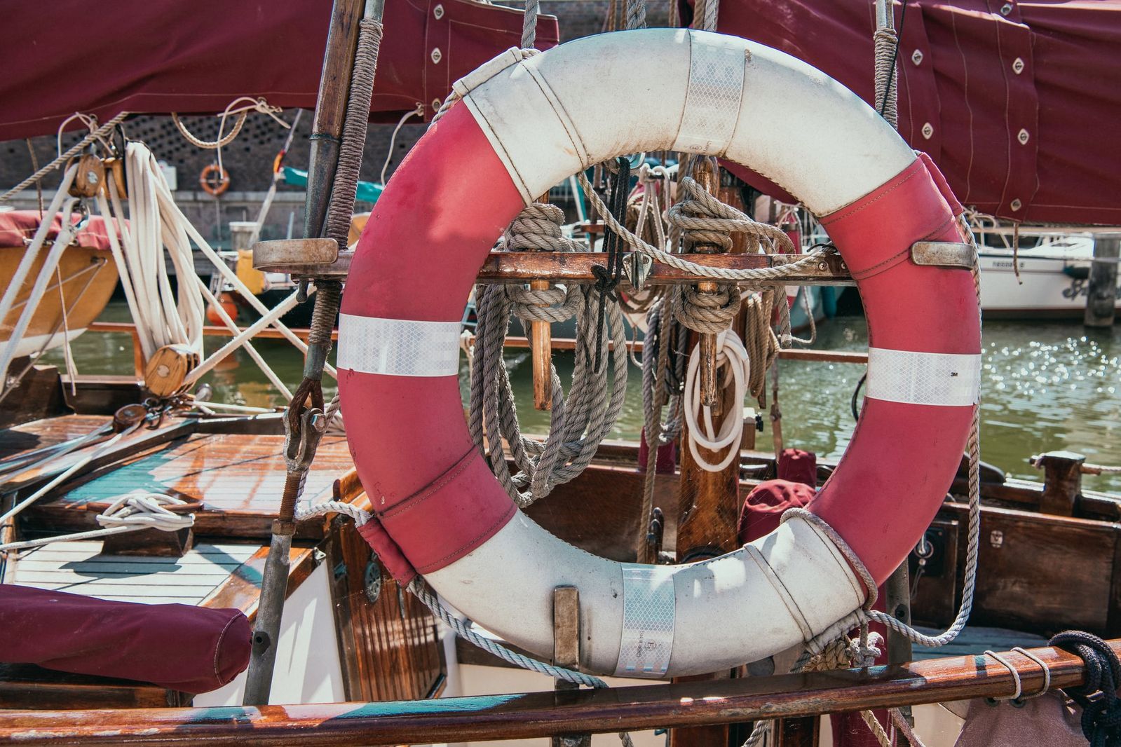 Leuchtend roter Rettungsring an einem Segelboot im Hafen von Stralsund, detailreich fotografiert mit maritimer, nostalgischer Atmosphäre