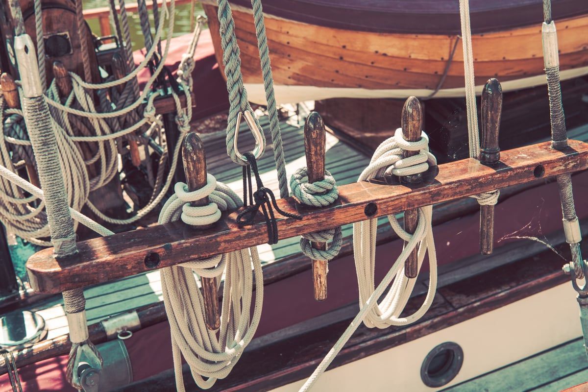 Detailaufnahme eines traditionellen Segelschiffs mit Holzdeck, Seilen und Segeln im Hafen von Stralsund, maritim und nostalgisch in Szene gesetzt
