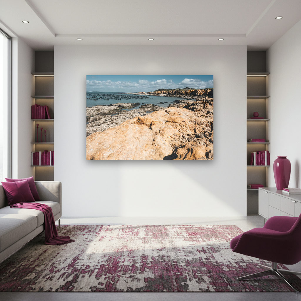 Sonnige Felsküste in der Bretagne bei Ebbe mit zahlreichen Holzbalken von Austernbänken im Meer.