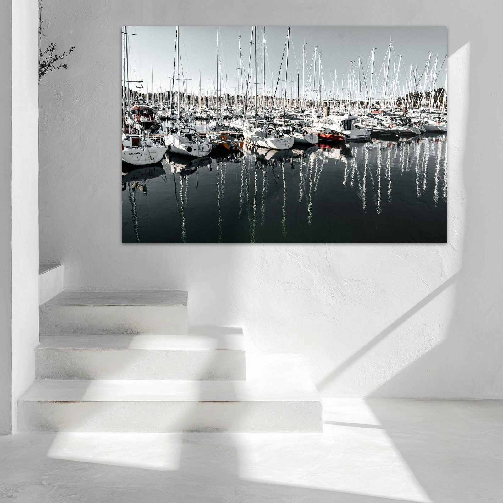 Mehrere Segelboote liegen ruhig nebeneinander im Hafenbecken, das Wasser spiegelt die Boote und die sanfte Lichtstimmung wider.